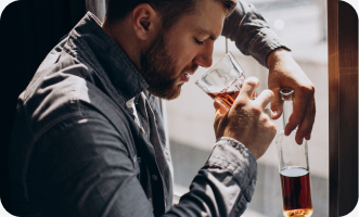 Man drinking whiskey near a window.
