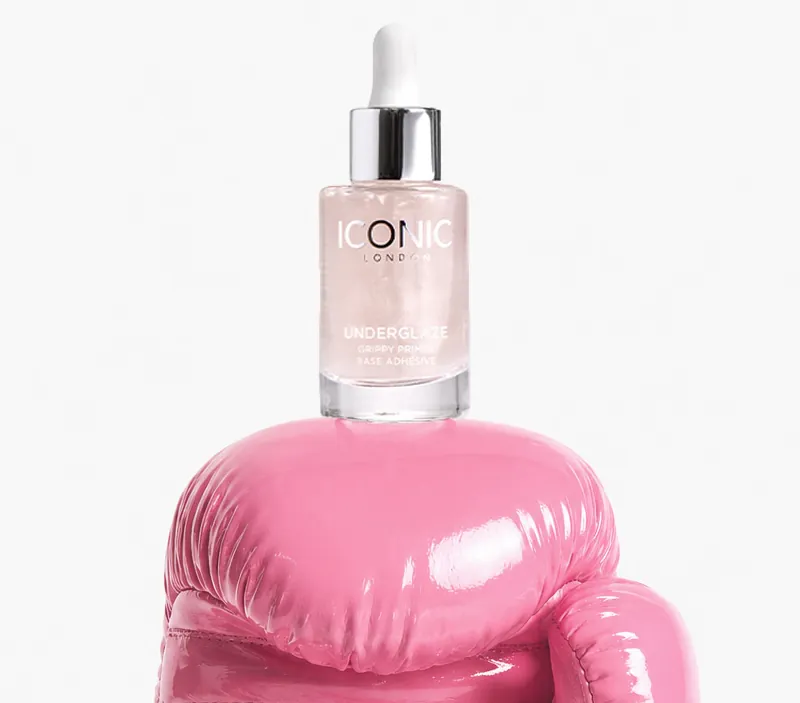 A bottle of ICONIC LONDON Underglaze primer sitting on top of a shiny pink boxing glove.