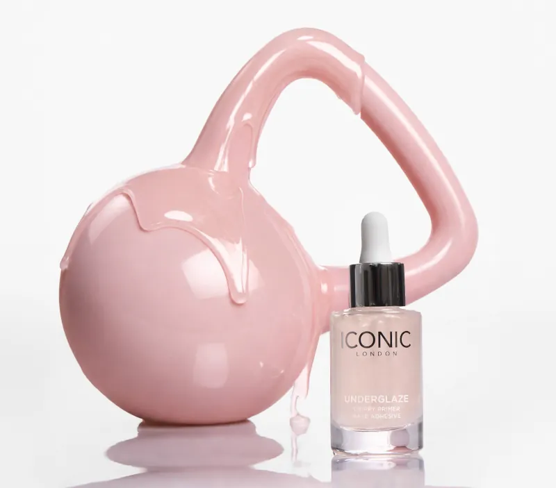 A bottle of Iconic London Underglaze primer next to a pink kettlebell with pink liquid dripping down it.
