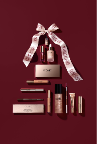 Assorted cosmetic products with a ribbon on a burgundy background.