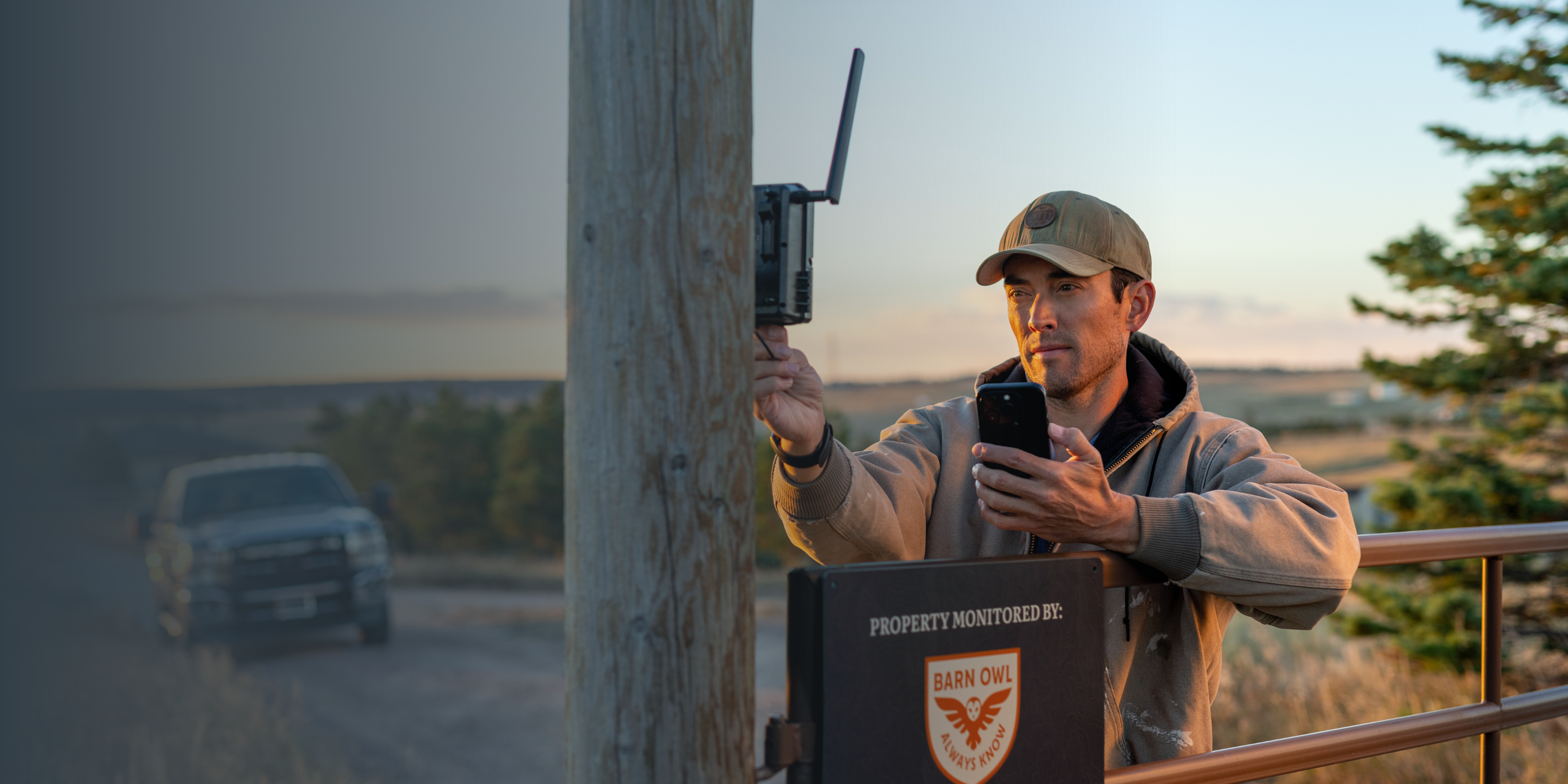 Person adjusting a device on a pole, holding a smartphone.