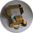 An open gift box with a lit candle, a citrus slice, and various small products.