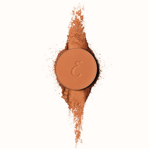 Round makeup powder with letter 'E' surrounded by scattered powder.