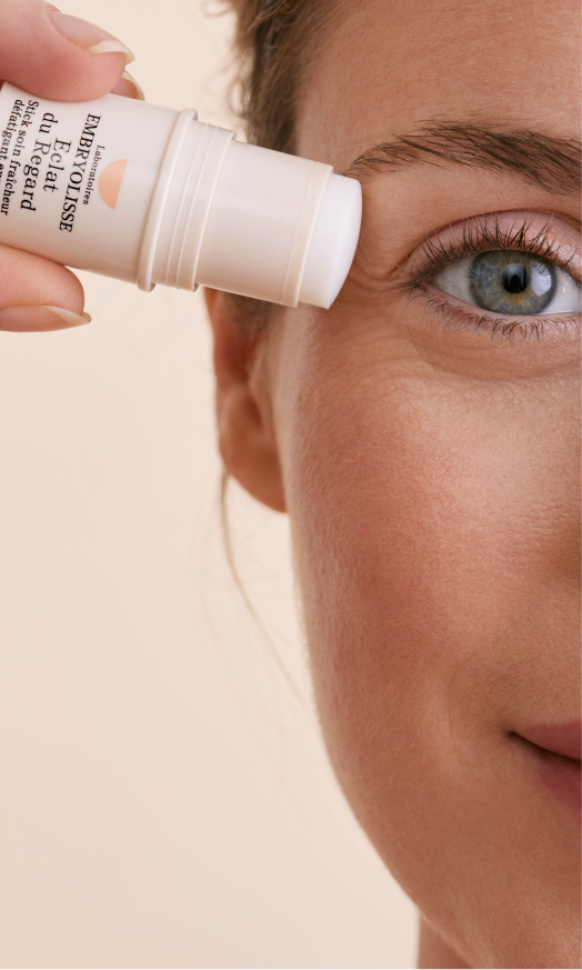 Woman applying cream stick near her eye.