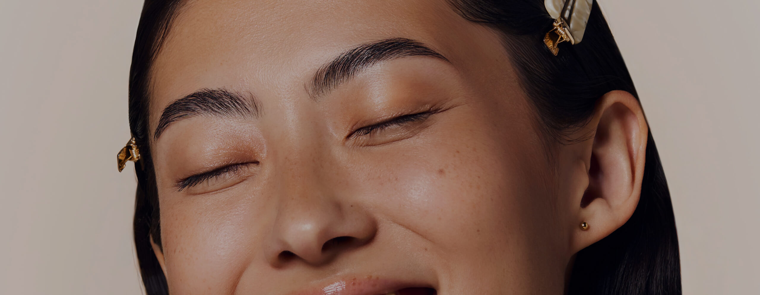 Close-up of a person smiling with eyes closed and hair clips visible.