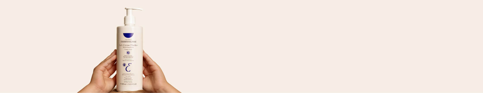 Hands holding a bottle of skincare lotion with a pump dispenser.