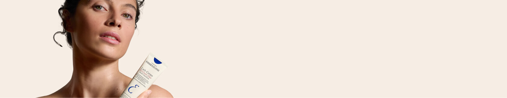 Woman with long hair making a playful face against a plain background.