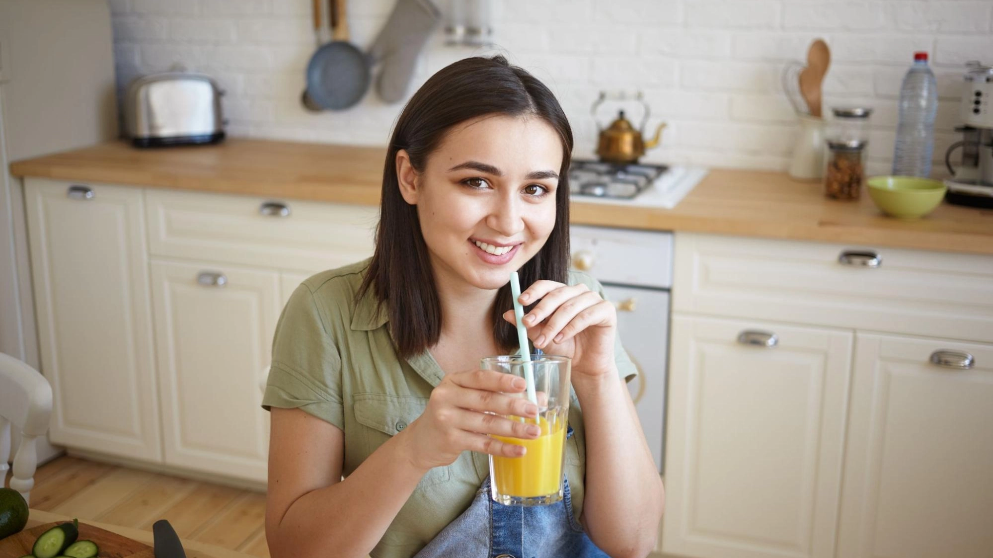 Person drinking orange juice in a kitchen.