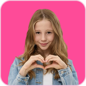 A young girl in a denim jacket makes a heart shape with her hands against a pink background.
