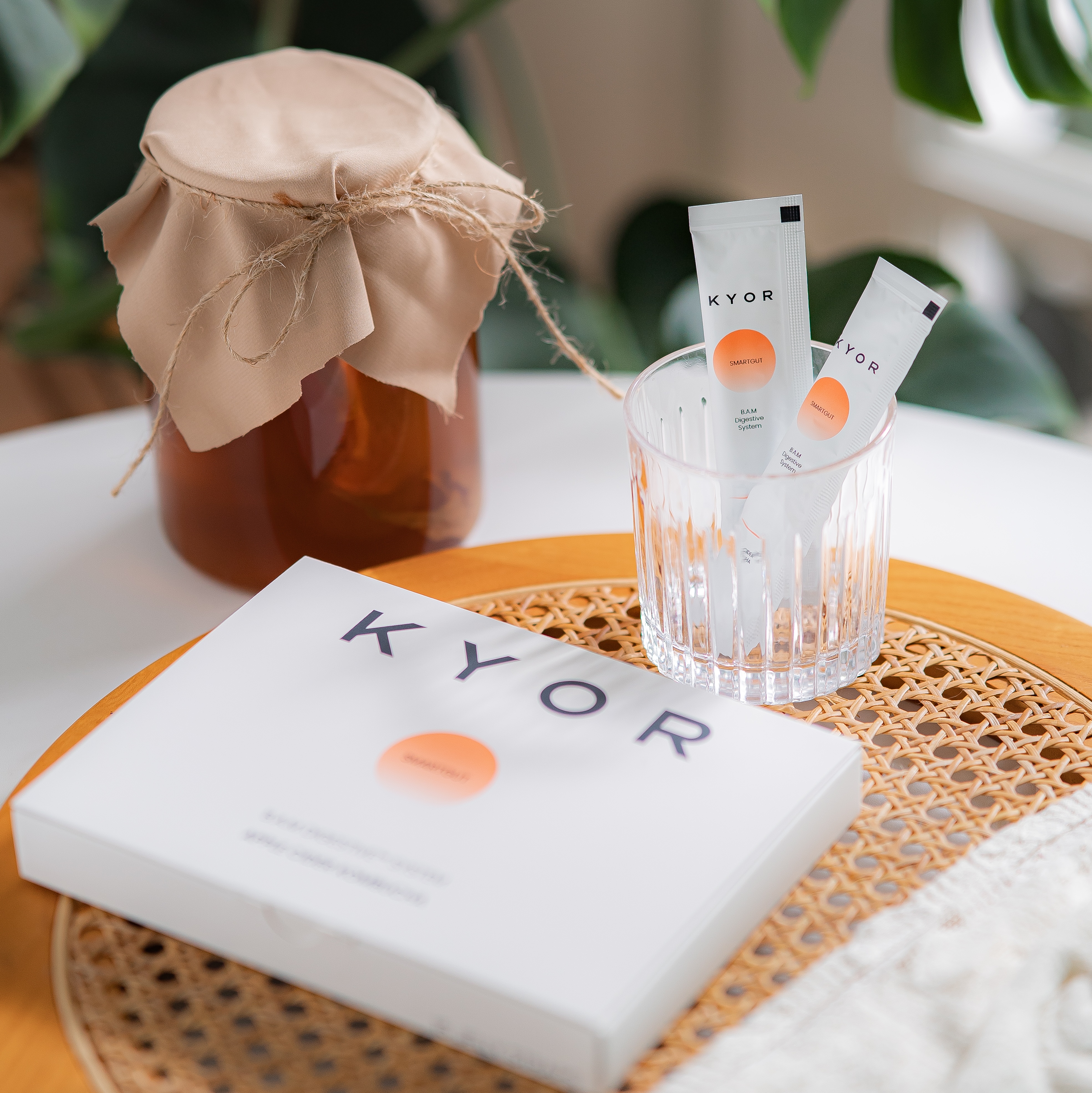 KYOR supplement box and packets on a rattan tray next to a jar of kombucha.