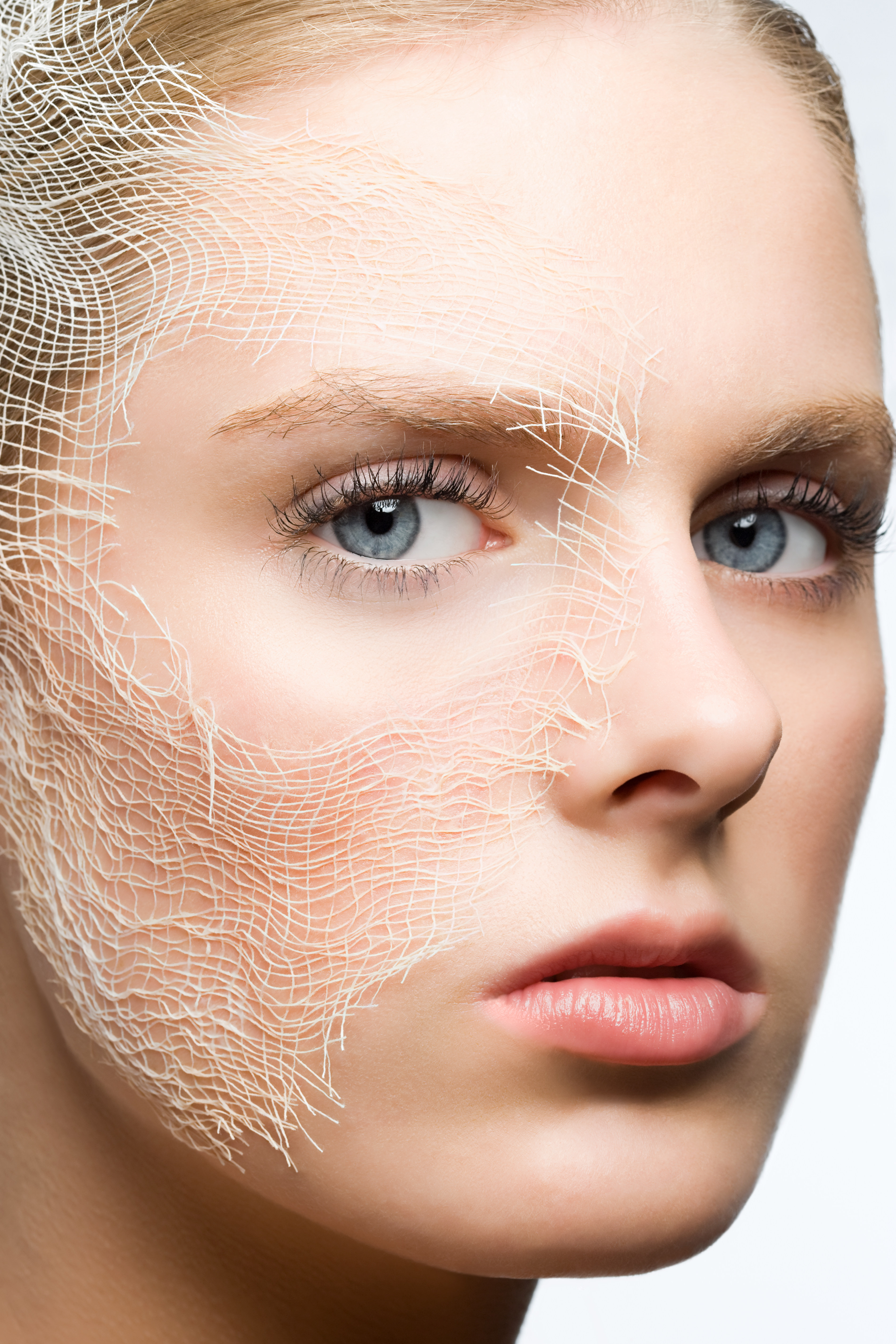 A close-up of a woman's face with a white, mesh-like material applied to her skin.