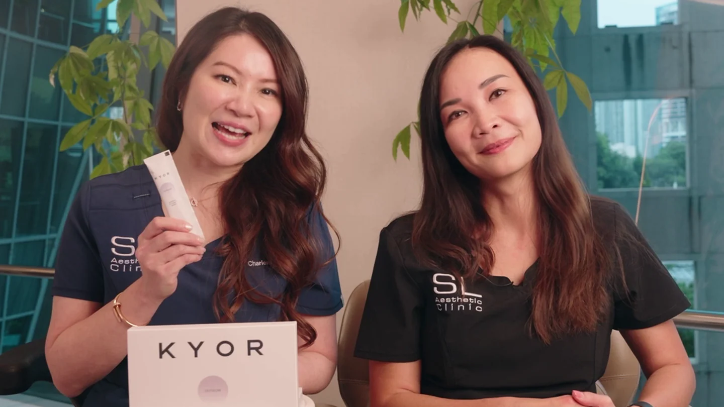 Two women in clinic uniforms present a skincare product called Kyor while sitting in an office.