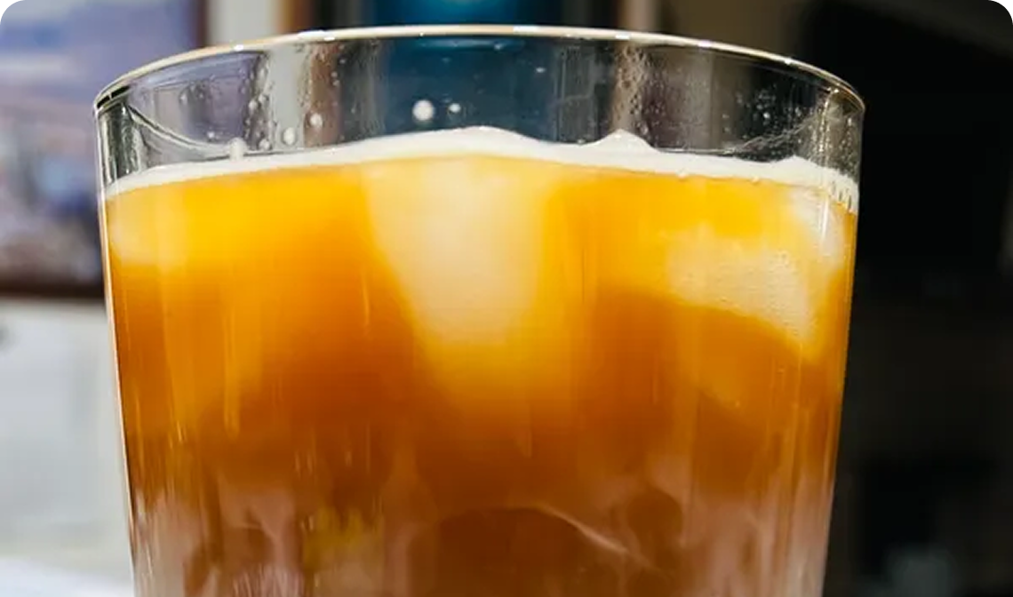 Close-up of a glass filled with orange liquid and ice.