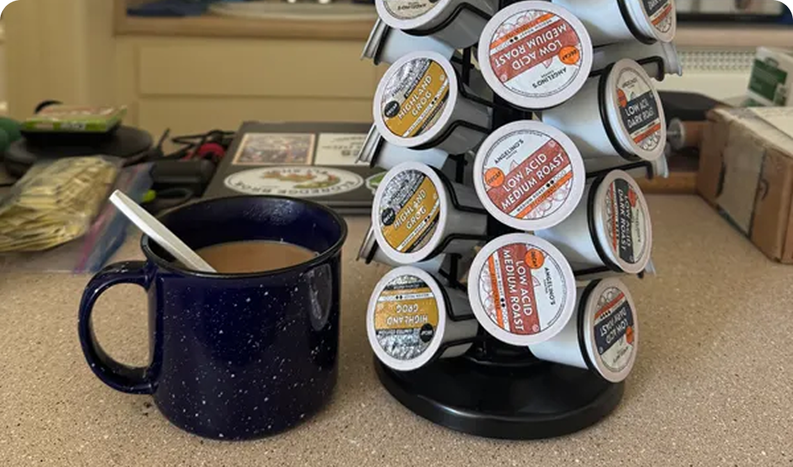 Coffee pods on a rack beside a blue mug with a spoon.
