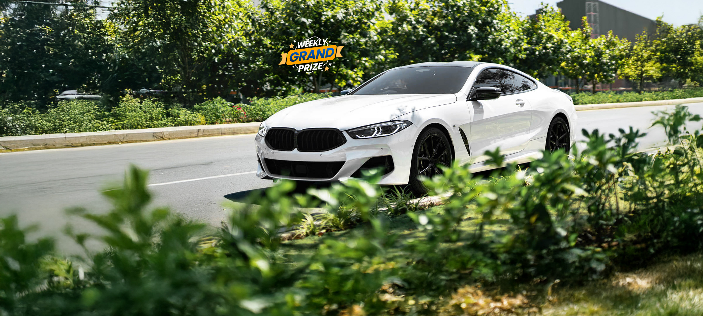 A white BMW coupe parked on the side of a road with a 'Weekly Grand Prize' graphic.