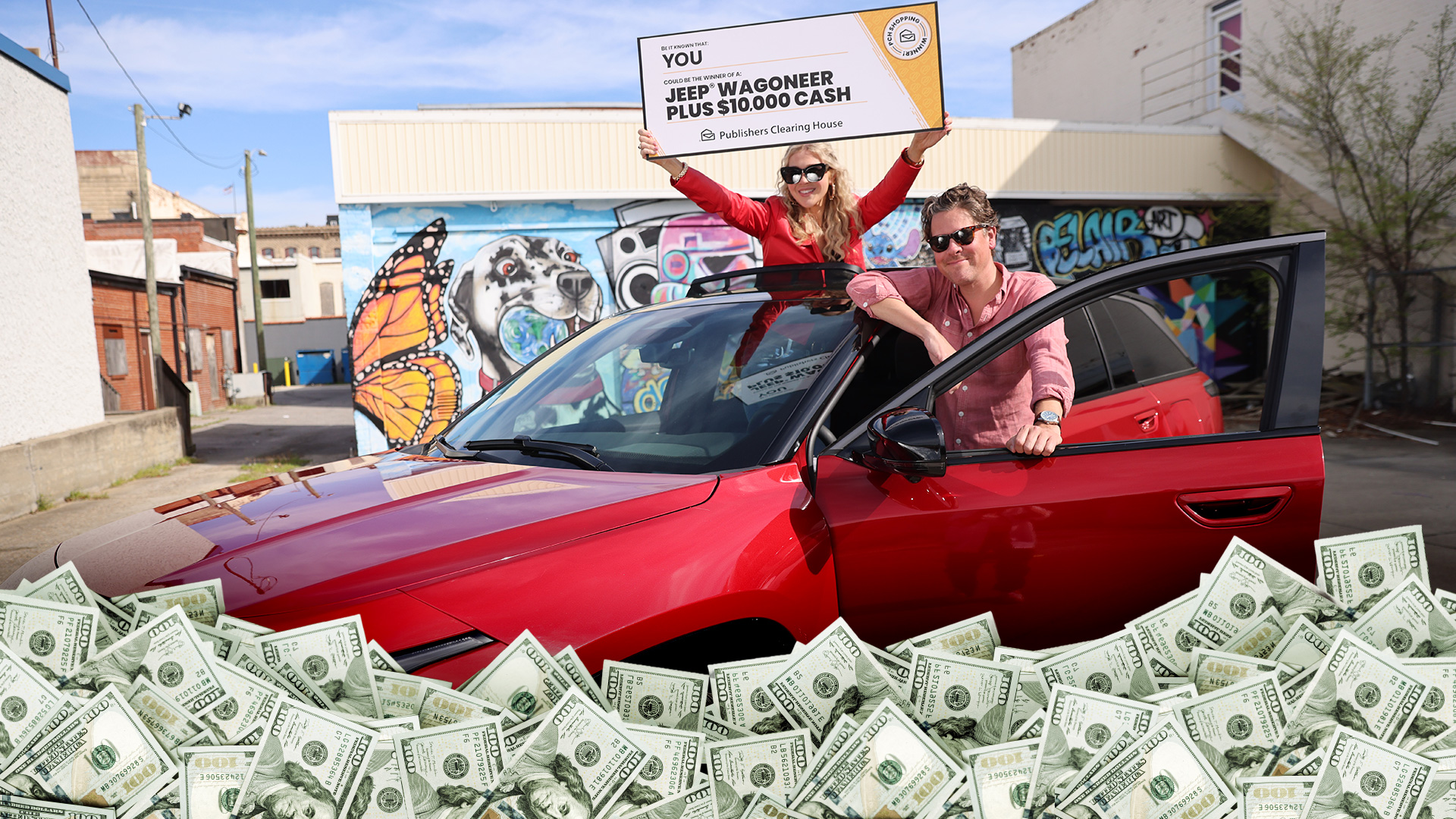 A couple poses with a red SUV, holding a Publishers Clearing House check over a pile of cash.