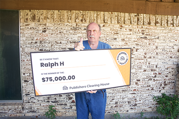 A man gives a thumbs-up while holding a large Publishers Clearing House check for $75,000.