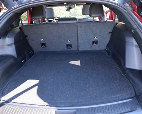 The empty, carpeted cargo area of a car, viewed from the open rear hatch.