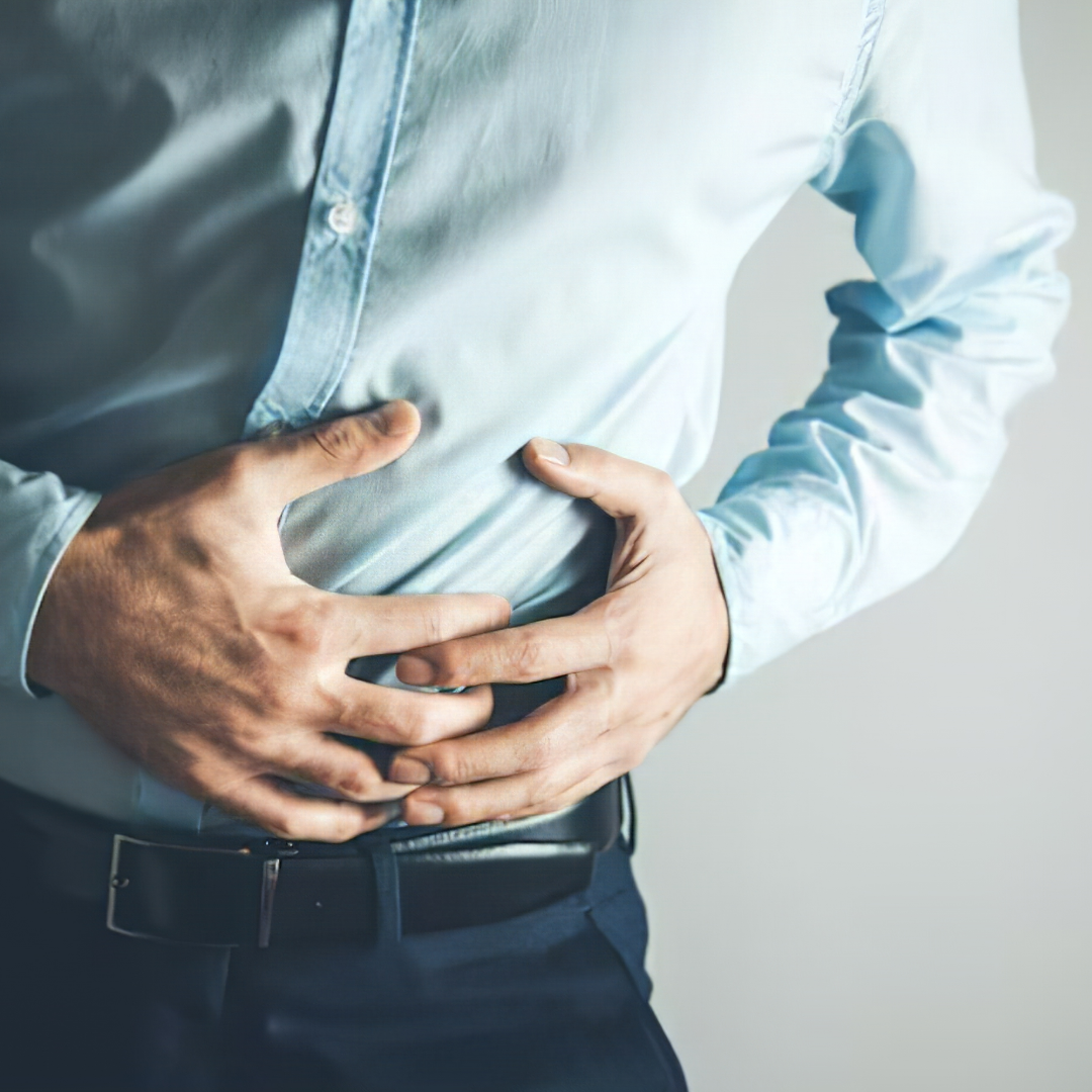 Person in a blue shirt holding their stomach in discomfort.