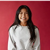 Smiling woman in a white sweater against a red background.