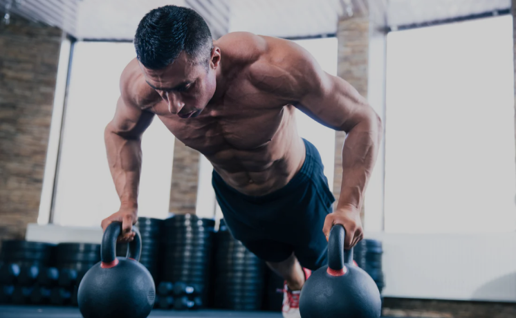 Man performing push-ups on kettlebells in a gym.