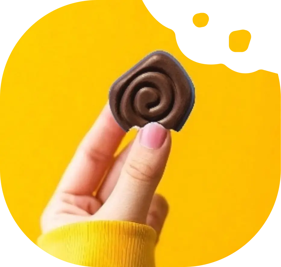 A hand in a yellow sweater holds a swirl-shaped piece of chocolate against a yellow circular background.