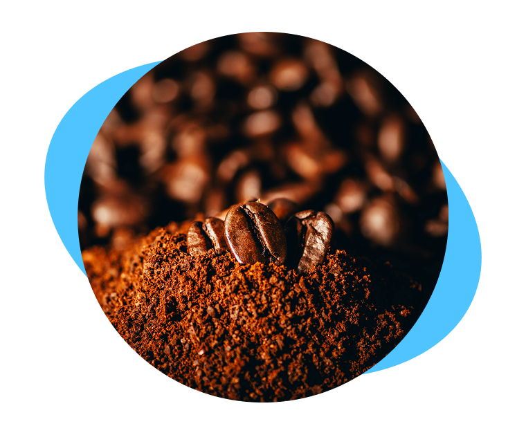 A close-up of roasted coffee beans resting on a mound of fresh coffee grounds.