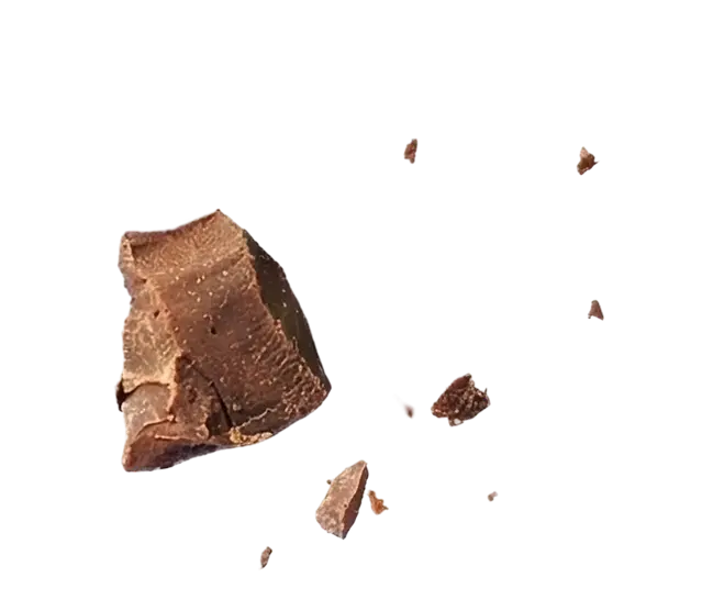 A large chunk and several smaller pieces of milk chocolate against a solid green background.