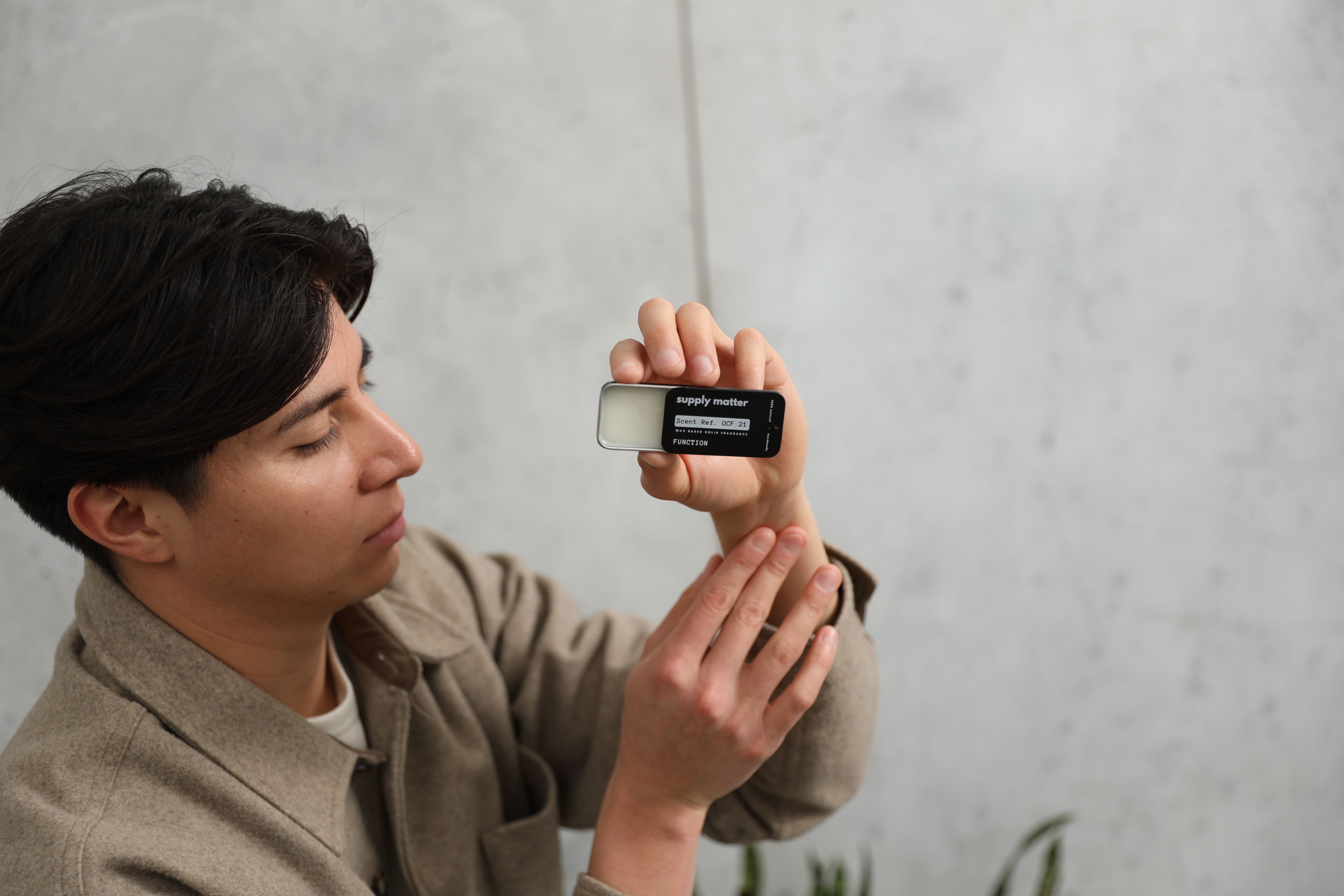 Person holding a small rectangular object with text, against a plain background.