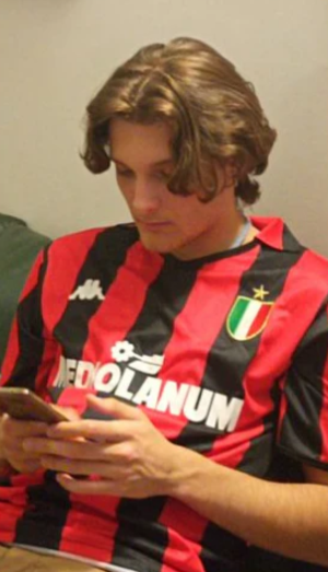 Person in a red and black striped football jersey using a smartphone.