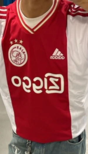 Person wearing a red and white Ajax soccer jersey with Adidas logo.