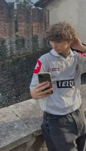 A person in a red and black sports jersey looking at a phone.