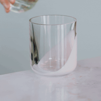 Water being poured into a clear glass on a marble surface.