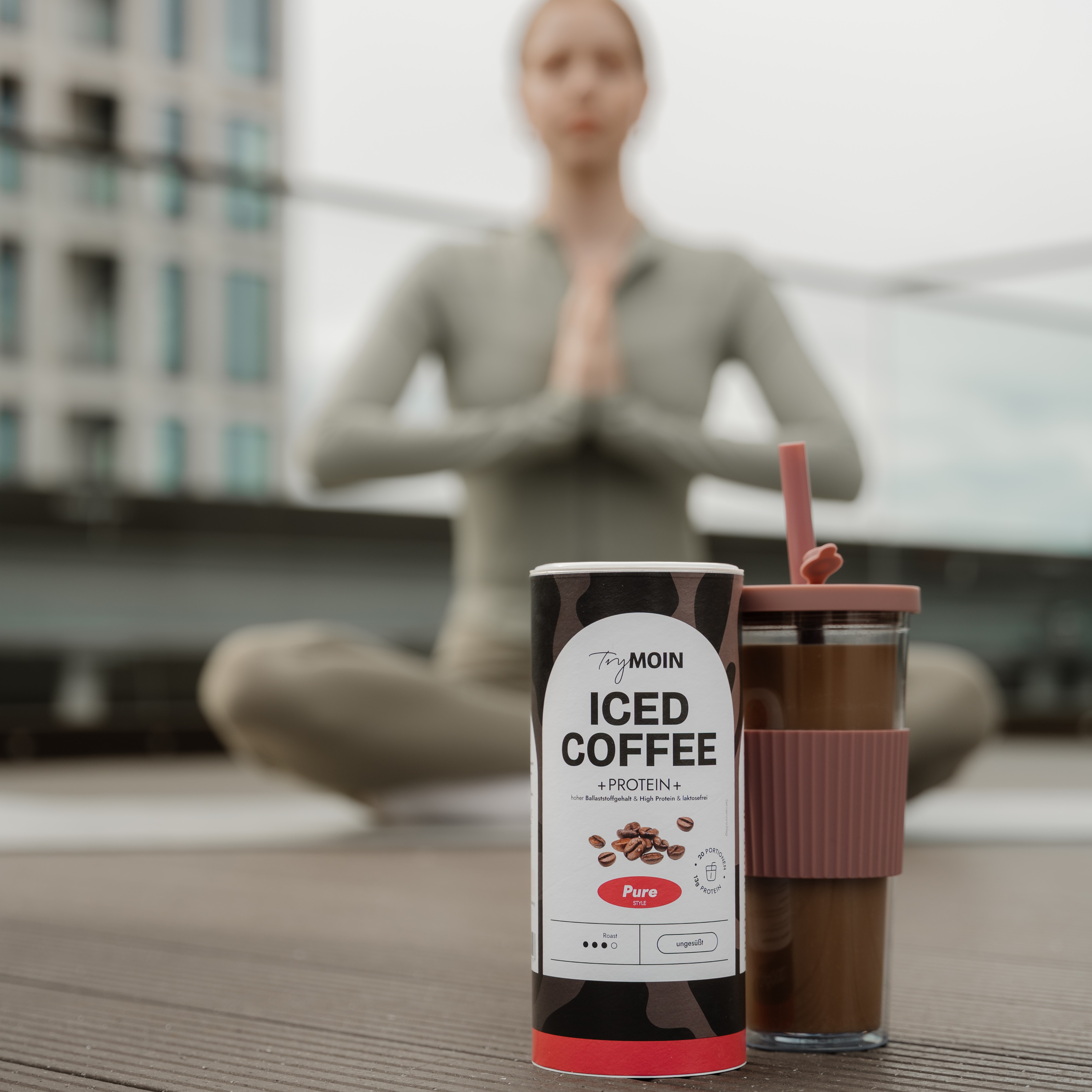 Iced coffee container and cup with blurred person meditating in background.