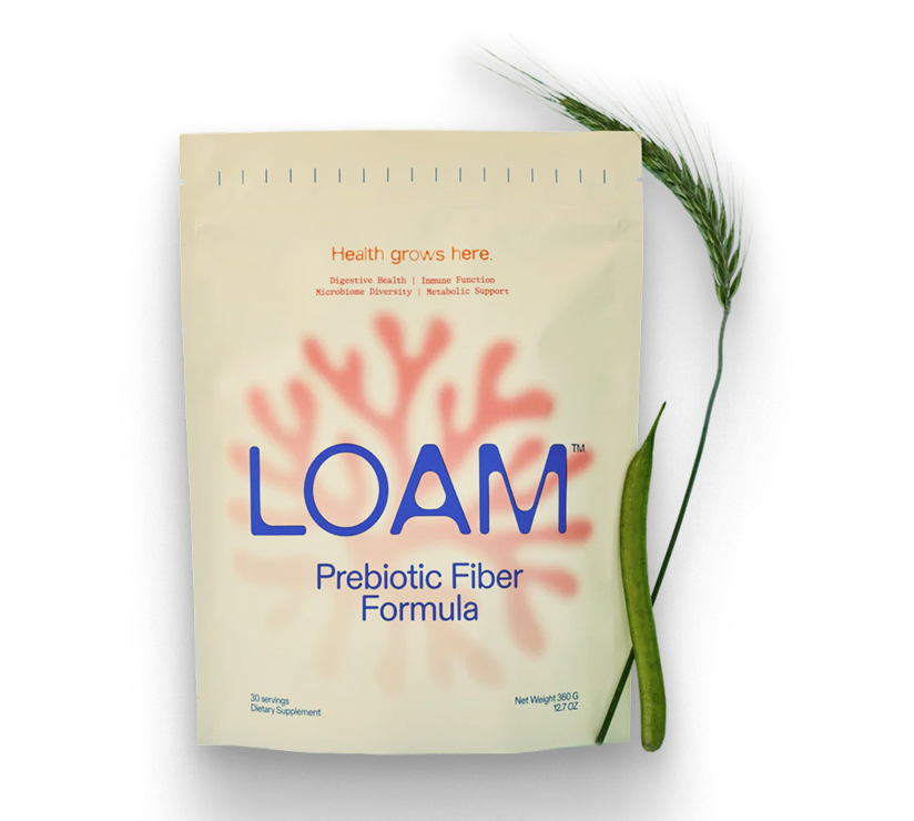 A pouch of LOAM Prebiotic Fiber Formula next to a stalk of wheat and a green bean pod.