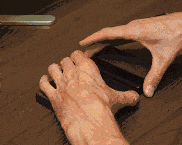 Hands shuffling a deck of playing cards on a table.