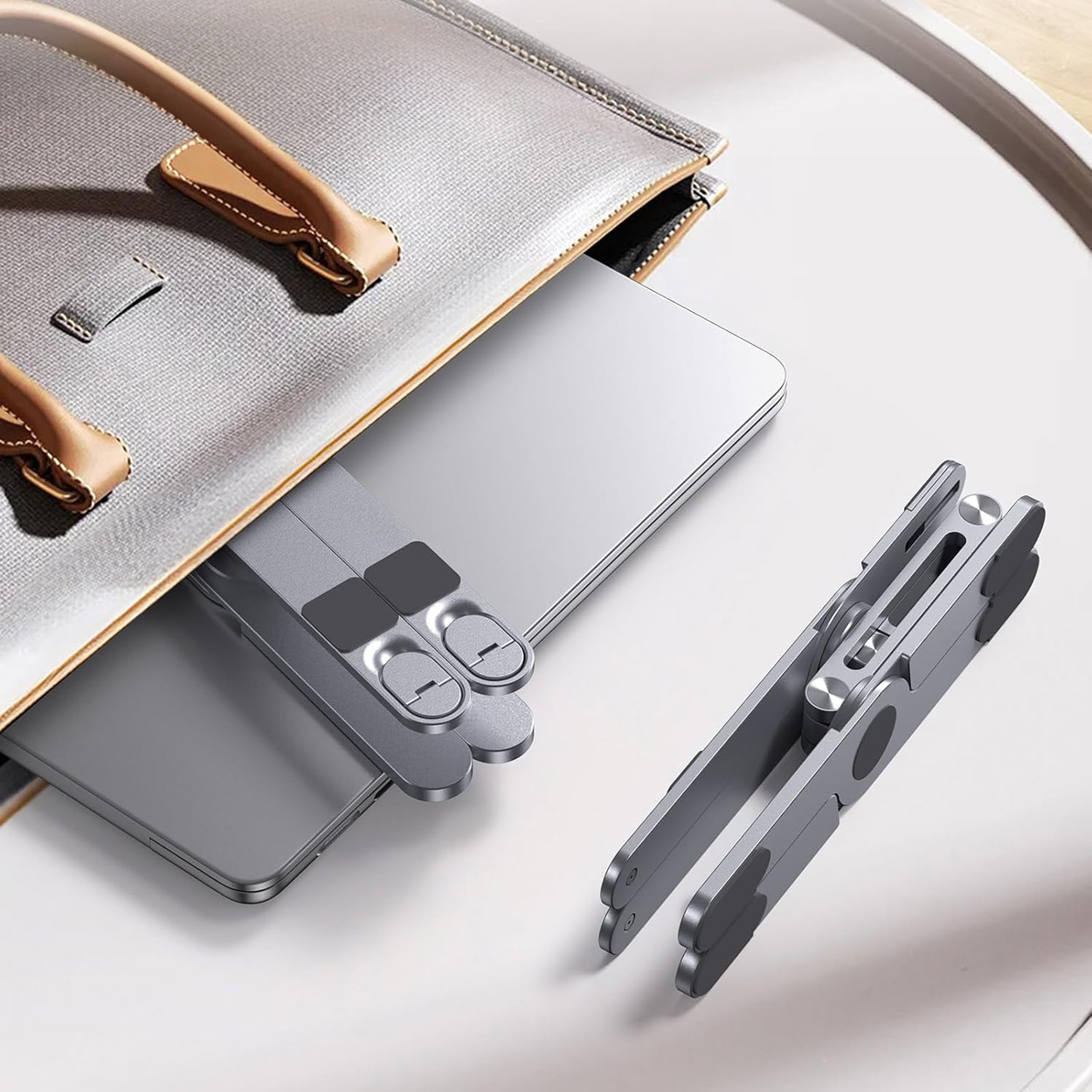 Laptop and two devices partially visible in a beige bag.