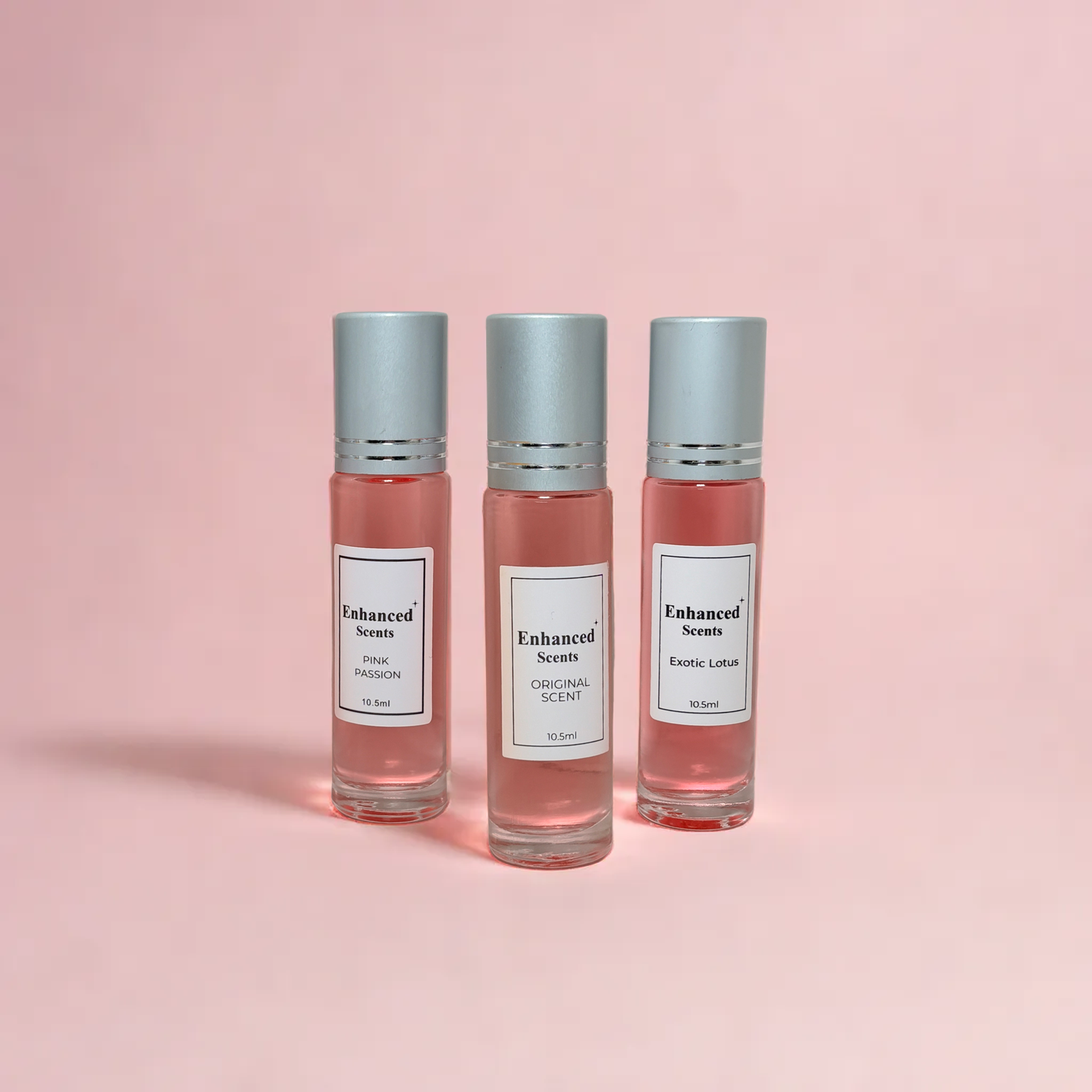 Three perfume bottles labeled 'Enhanced Scents' on a pink background.