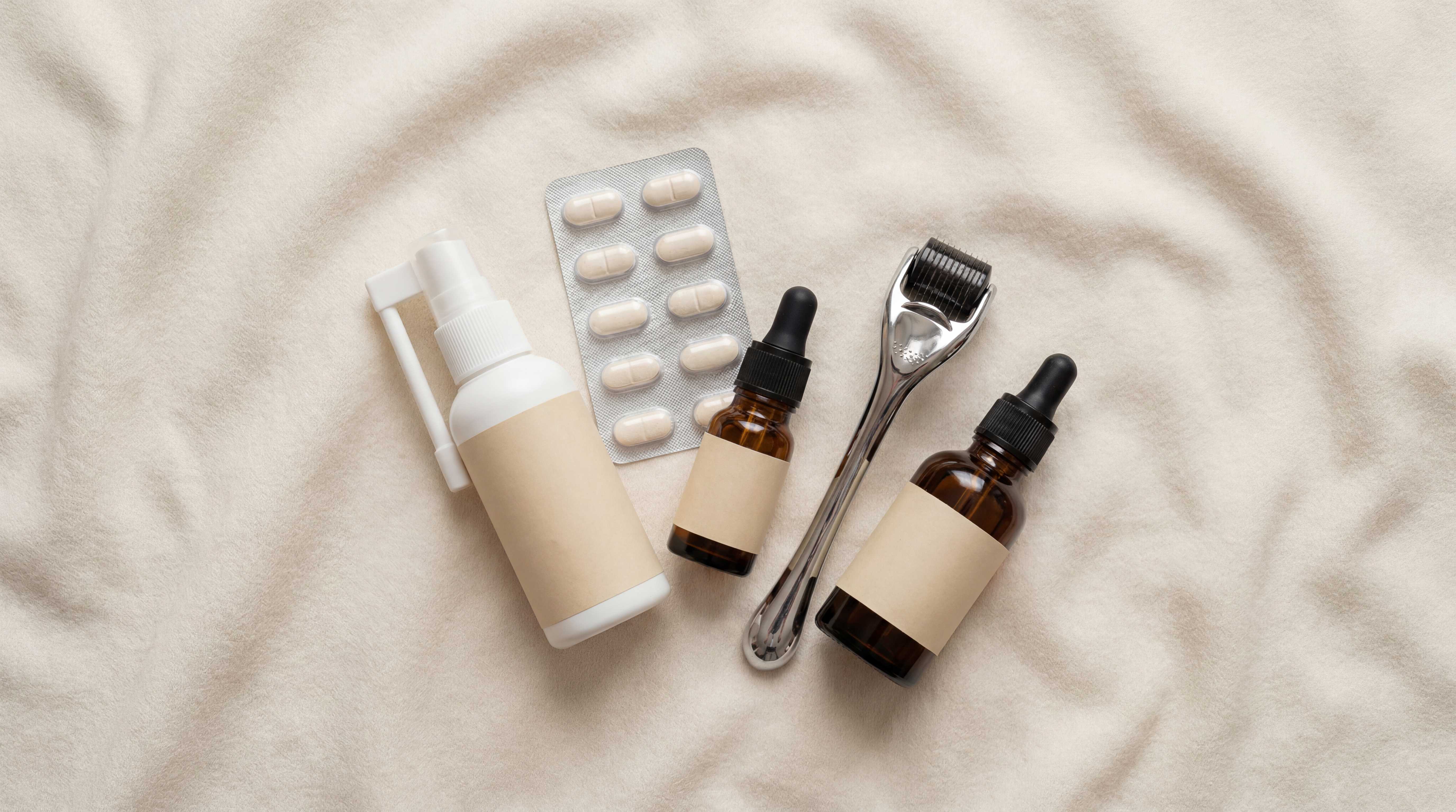 Hair treatment products including a derma roller, spray, pills, and serum bottles on a textured beige background.