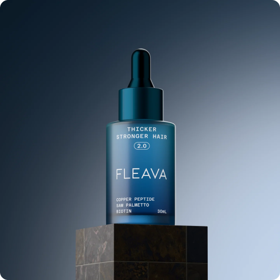 A blue dropper bottle of Fleava hair serum sitting on a dark marble pedestal against a blue background.