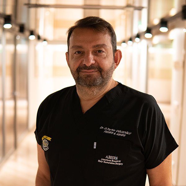 Man in black scrubs standing in a well-lit hallway.