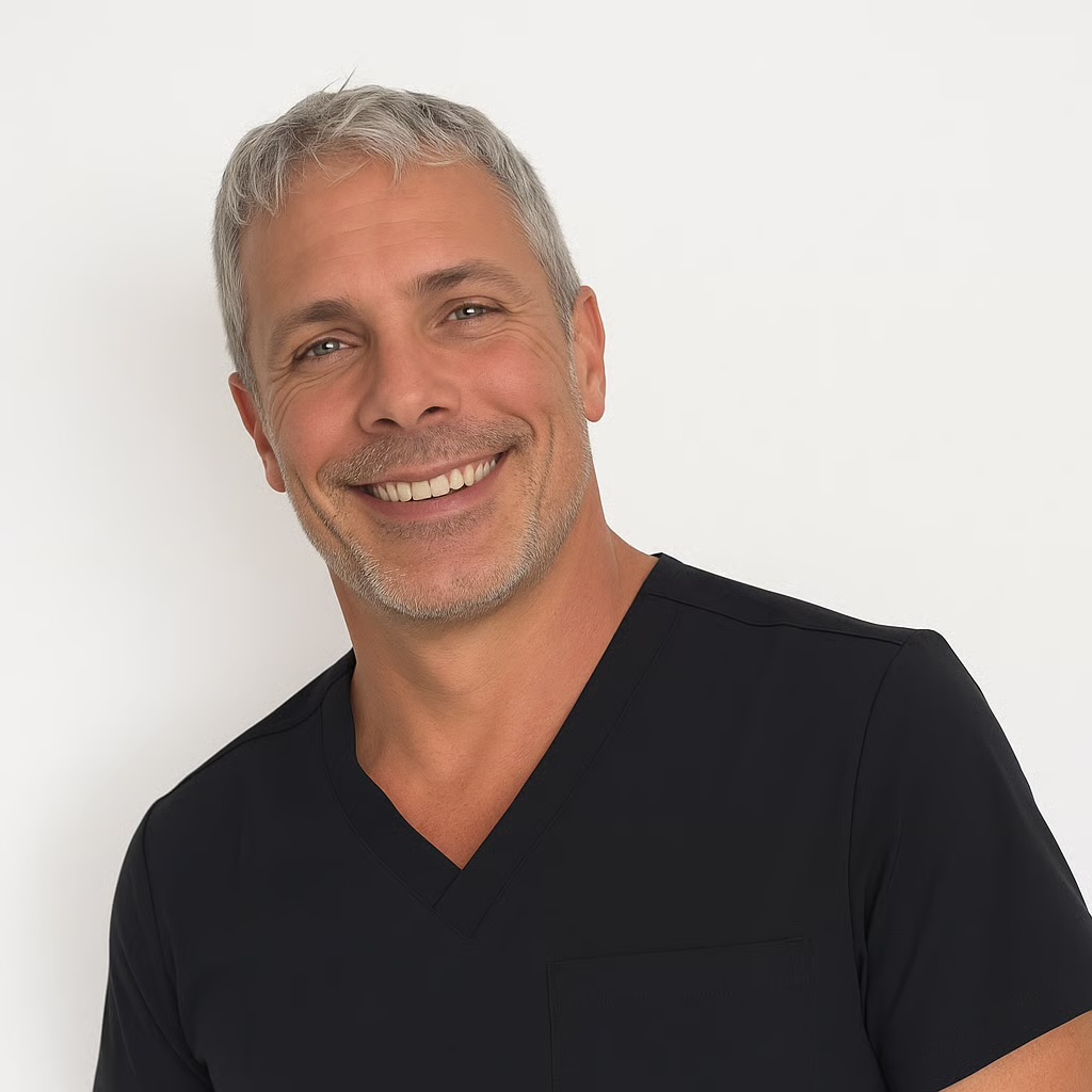 A smiling, gray-haired man wearing a black v-neck scrub top against a plain white background.