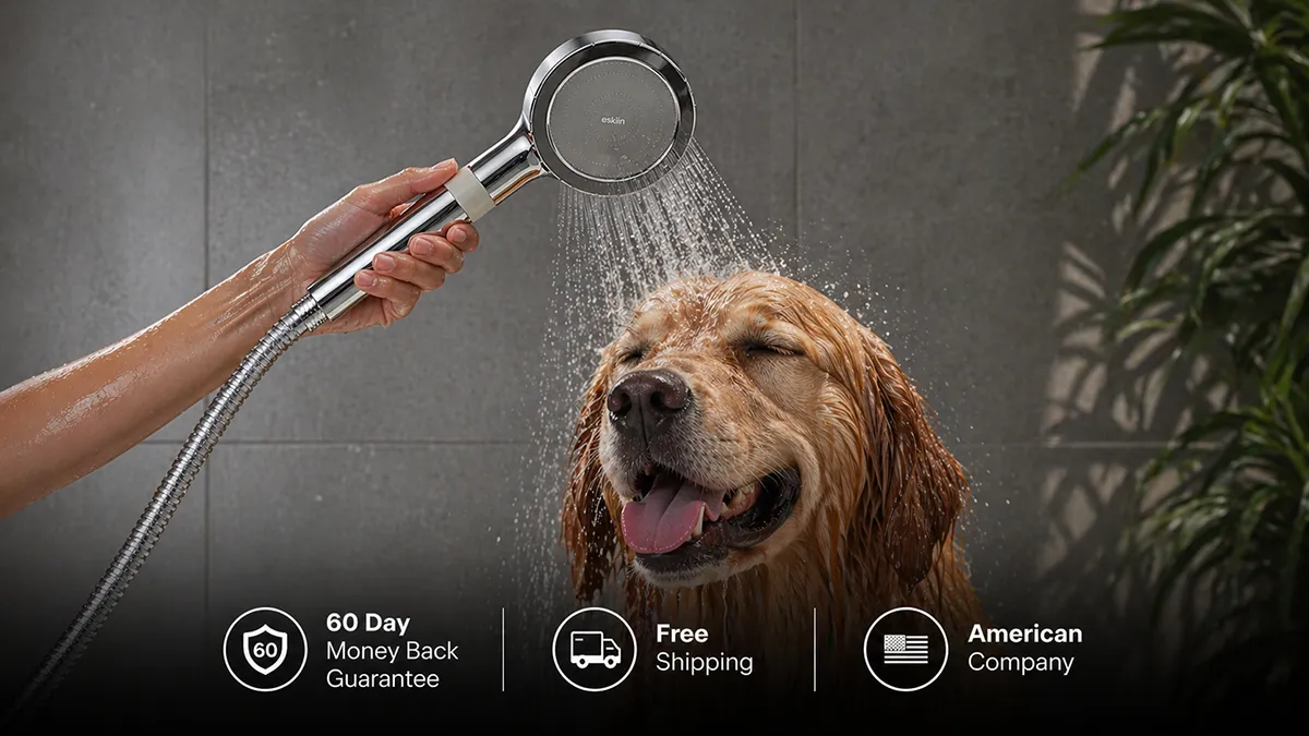 A person washes a happy golden retriever with a handheld shower head in a bathroom.