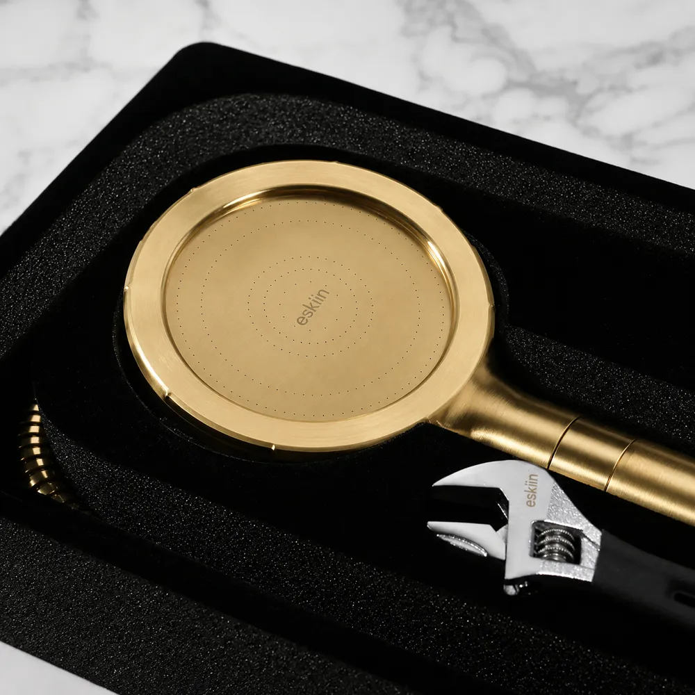 A gold handheld shower head and an adjustable wrench resting in a black foam-lined case.