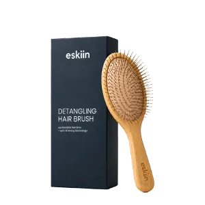 An eskiin brand wooden detangling hair brush is displayed next to its black rectangular packaging on a white background.