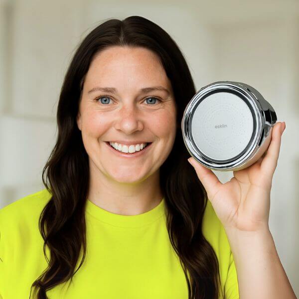 Person smiling, holding a round metallic device with a logo.