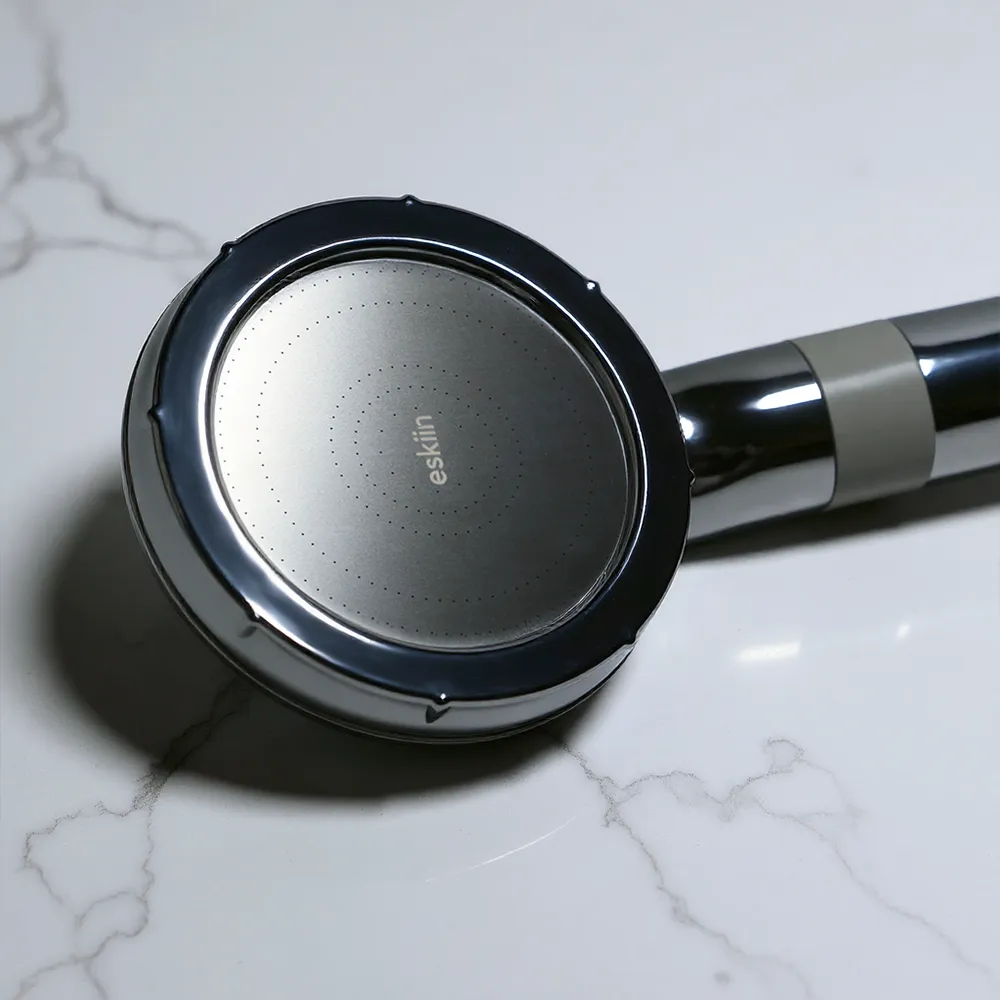 Close-up of a metallic showerhead on a marble surface.