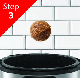 A Curry ball above an open air fryer with a tiled wall background.