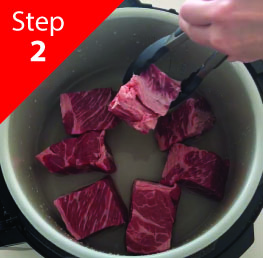 'Beef cubes being placed into a pot using tongs, labeled Step 2.'