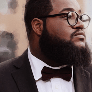 Man with glasses and beard wearing a suit and bow tie.